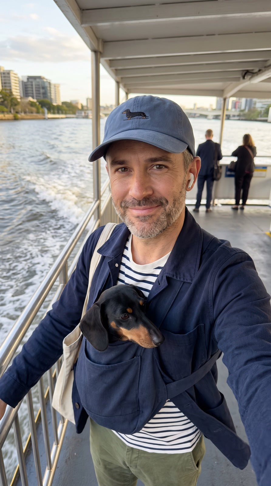 James wearing the washed-blue Dachshund Cap with his dachshund on a Brisbane ferry
